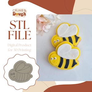 May include: A digital STL file for 3D printing a bee-shaped cookie cutter. The image shows a close-up of two decorated cookies shaped like bees, with yellow bodies, black stripes, white wings, and black eyes. The text "STL FILE" and "Digital Product for 3D Printing" is also visible.