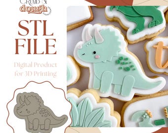 May include: A collection of dinosaur-shaped cookies, including a light green triceratops with white accents and a matching outline. The cookies are decorated with white icing and sit on a white surface. The image also includes the text "STL FILE" and "Digital Product for 3D Printing".