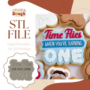 May include: An image featuring a collection of decorated cookies. The central cookie reads "Time Flies When You're Turning One" in red and white icing. The image also includes an STL file graphic for 3D printing.