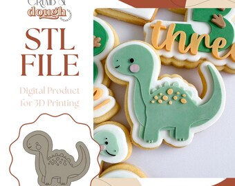 May include: An image of a green dinosaur cookie with white icing and yellow accents. The cookie is decorated with a cute dinosaur design. The image also includes the text "STL FILE" and "Digital Product for 3D Printing".
