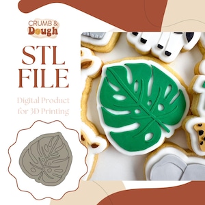 May include: A digital download STL file for a 3D printed cookie cutter in the shape of a green monstera leaf. The image shows a cookie decorated with green icing in the shape of a monstera leaf.