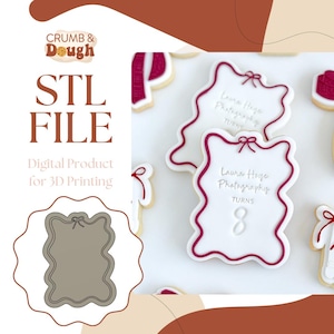 Puede incluir: Un archivo STL descargable digitalmente para un cortador de galletas impreso en 3D. El cortador tiene la forma de un rectángulo con esquinas redondeadas y un lazo en la parte superior. El cortador está diseñado para crear galletas con el texto "Laura Hoge Photography Turns 8".