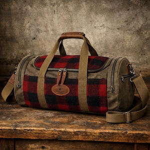 May include: A duffel bag with a red and black plaid center panel, olive green canvas sides, and brown leather accents. It has a top handle, a shoulder strap, and a leather tag.