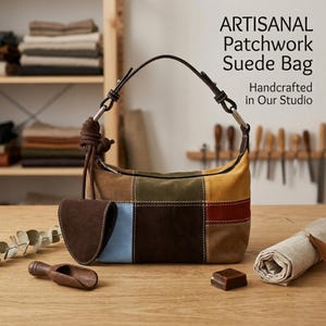 May include: Artisanal patchwork suede bag with a brown leather strap and a small matching pouch. The bag features a colorful patchwork design with squares of brown, blue, yellow, green, and red suede. The text on the image says "Handcrafted in Our Studio."