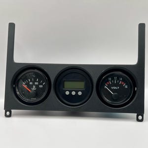 Könnte beinhalten: Schwarzes Armaturenbrett mit drei runden Anzeigen. Die linke Anzeige zeigt die Temperatur in Celsius an, die Mitte hat eine Digitalanzeige und die rechte Anzeige zeigt die Spannung an. Das Panel hat zwei vertikale Verlängerungen.