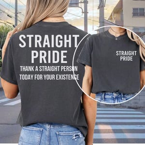 Puede incluir: Camiseta gris oscuro con las palabras "STRAIGHT PRIDE" impresas en blanco en la espalda y en la parte delantera. La parte trasera de la camiseta también incluye el texto "THANK A STRAIGHT PERSON TODAY FOR YOUR EXISTENCE".