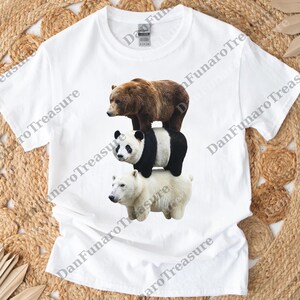 May include: White t-shirt featuring a graphic of three bears stacked on top of each other: a brown bear, a panda bear, and a polar bear. The bears are realistically rendered. The shirt is made of a soft material.