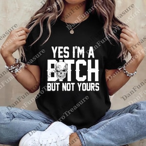 May include: Black t-shirt with the text "YES I'M A BITCH BUT NOT YOURS" in white block letters. A skull graphic is centered within the word "BITCH". The shirt is a casual wear item.