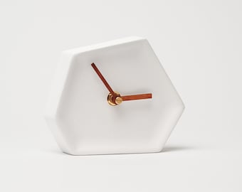 May include: White hexagonal clock with gold hands and a wooden hour hand.