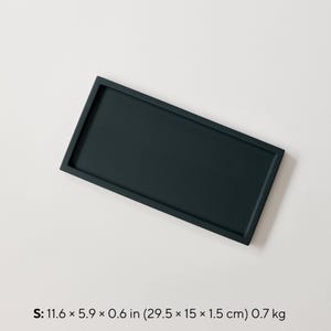 Op de afbeelding: Een rechthoekige, donkerblauwe dienblad met opstaande randen. De dienblad meet 29,5 x 15 x 1,5 cm en weegt 0,7 kg. De dienblad is effen van kleur en lijkt van hout of een vergelijkbaar materiaal te zijn.