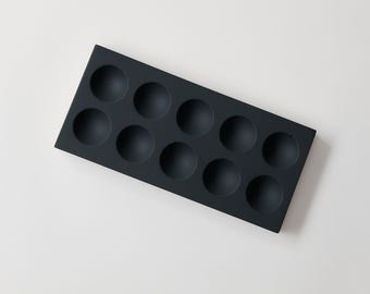 May include: A black rectangular tray with 10 round depressions, perfect for organizing small items.