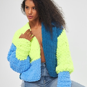 Può includere: Un cardigan di maglia colorato con un design a blocchi di colore blu, verde e giallo. Il cardigan ha una vestibilità rilassata e maniche lunghe.