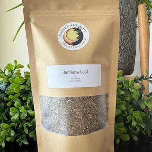 Op de afbeelding: Een bruine papieren zak met een doorzichtig venster, gevuld met gedroogde Damiana Leaf. De zak heeft een wit etiket met de tekst "Damiana Leaf" en "100% Organic Turnera Diffusa". De zak heeft ook een ronde sticker met de tekst "Nature's Remedy apothecary".