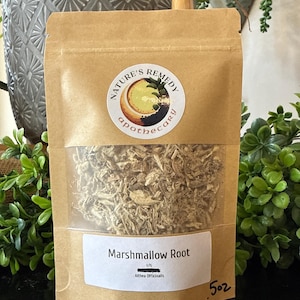 May include: A brown paper bag with a clear window containing dried marshmallow root. The bag has a white label with the text "Marshmallow Root" and "Althea Officinalis". The bag also has a "Nature's Remedy Apothecary" sticker.