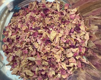 May include: Close-up of dried rose petals in a stainless steel bowl. The petals are a mix of light tan, pink, and deep magenta, with a slightly crumpled texture. The petals fill the bowl, suggesting a bulk quantity.