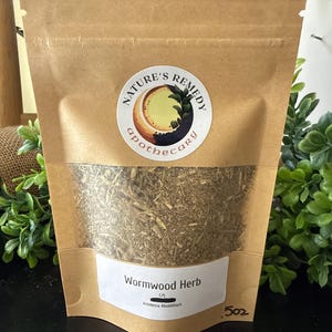 May include: A brown paper bag with a clear window containing dried wormwood herb. The bag has a white label with the text "Wormwood Herb" and the brand's logo. The bag is labeled as 5 oz.