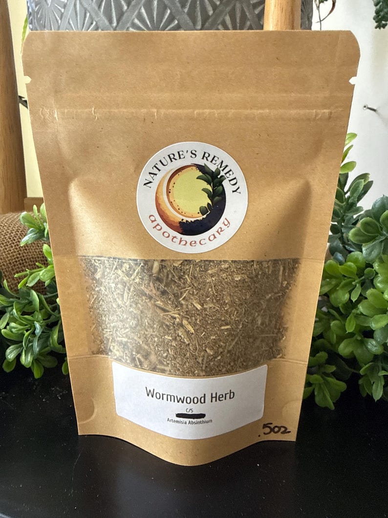 May include: A brown paper bag with a clear window containing dried wormwood herb. The bag has a white label with the text "Wormwood Herb" and the brand's logo. The bag is labeled as 5 oz.