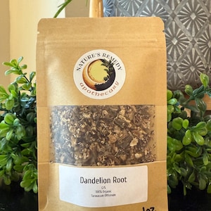 May include: A brown paper bag of dandelion root with a clear window, labeled "Dandelion Root" and "100% Organic." The bag features a circular sticker with the text "Nature's Remedy Apothecary." The bag contains 1 oz of product.