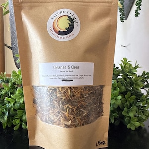 May include: A brown paper bag of herbal tea blend, labeled "Cleanse & Clear." The bag has a clear window showing the tea leaves. The label includes the ingredients: burdock root, dandelion, marshmallow leaf, ginger, licorice root, peppermint, calendula, red clover, nettle, and alfalfa.