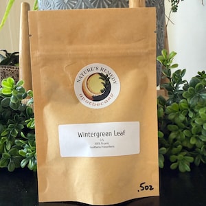 Puede incluir: Una bolsa de papel marrón con la etiqueta "Wintergreen Leaf" y una pegatina redonda que dice "Nature's Remedy Apothecary". La bolsa contiene 14,17 gramos de Gaultheria Procumbens 100% orgánica.