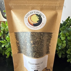 May include: A brown paper bag with a clear window displaying dried peppermint leaves. The bag has a white label with the text "Peppermint Leaf" and "Nature's Remedy Apothecary" logo. The bag contains 5 oz of product.