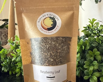 Peut inclure: Un sachet en papier brun avec une fenêtre transparente montrant des feuilles de framboisier séchées. Le sac porte une étiquette blanche avec le texte "Raspberry Leaf" et "Rubus idaeus". Le sac contient 142 grammes de produit.