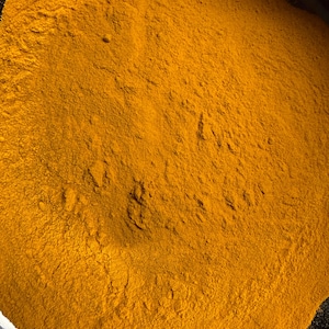 May include: Close-up of a pile of bright yellow turmeric powder. The powder has a fine, textured appearance, filling the frame. The color is a vibrant, warm yellow, suggesting freshness and quality. This image is suitable for culinary or health-related listings.