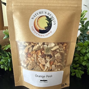May include: A brown paper bag with a clear window, filled with dried orange peel. The bag has a circular sticker with the words "Nature's Remedy Apothecary." The label reads "Orange Peel" and "1 oz."
