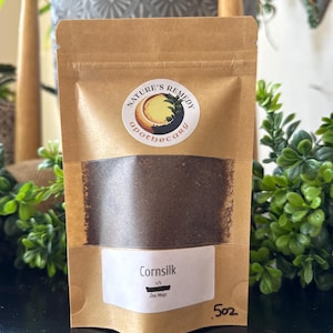 May include: A brown paper bag of cornsilk with a white label that reads "Cornsilk" and "Zea Mays". The bag has a circular sticker with the words "Nature's Remedy Apothecary". The bag contains 5 oz of cornsilk.