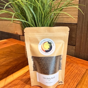 May include: A brown kraft paper stand-up pouch containing dried Tulsi Holy Basil leaves. The label features the text Nature's Remedy Apothecary, Tulsi (Holy Basil), C/S, Ocimum Tenuiflorum, and 5oz. A clear window reveals the dark green herbal contents.