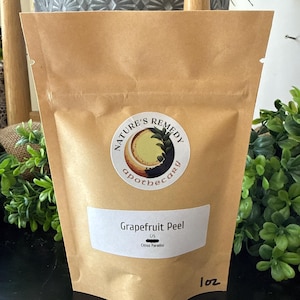 May include: A brown paper bag of grapefruit peel from Nature's Remedy Apothecary. The bag has a white label with the text "Grapefruit Peel" and "Citrus Paradisi". The bag also has a circular sticker with the words "Nature's Remedy Apothecary". The bag is 1 oz.
