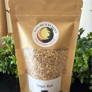 May include: A brown paper bag with a clear window, filled with dried ginger root. The bag has a circular sticker with the words "Nature's Remedy Apothecary". The label reads "Ginger Root" and "Zingiber Officinale". The bag is labeled "2oz".