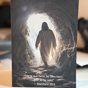 May include: A black and white image of a man walking out of a cave. The man is wearing a long robe and is walking towards a bright light. The text "He is not here; he has risen, just as he said." - Matthew 28:6 is at the bottom of the image.