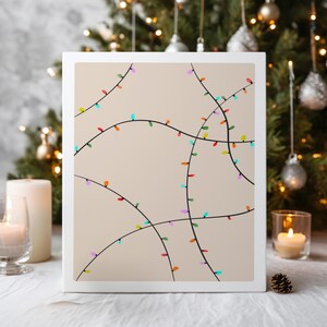 May include: A canvas print featuring a minimalist design of colorful Christmas lights on a neutral background. The lights are in various colors, including red, blue, green, and purple, with black lines. The artwork is framed in a white border.