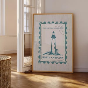 Puede incluir: Un cuadro vertical enmarcado con un diseño de sello postal en color verde azulado. El gráfico muestra un faro con el texto UNITED STATES POSTAGE 10c y NORTH CAROLINA. El fondo de la impresión tiene un sutil patrón de rayas verticales finas.