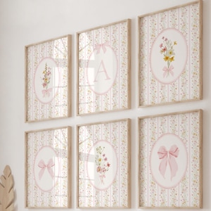 May include: Six framed wall art pieces with a floral and bow theme. Each piece features a light pink oval with a floral arrangement, a bow, or the letter "A" against a striped floral background. The frames are light wood.