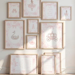 May include: A collection of framed art prints with a ballet theme. The prints feature illustrations of a ballerina, ballet shoes, a swan, a carriage, and an alphabet. The color palette is soft pink and white, with floral and bow accents. The frames are light wood.