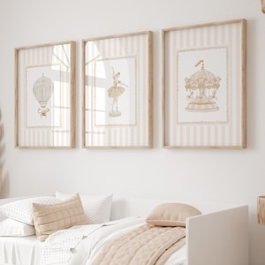 Puede incluir: Tres impresiones artísticas enmarcadas con un fondo a rayas beige claro y blanco. Las impresiones presentan ilustraciones de un globo aerostático, una bailarina y un carrusel, todo en tonos beige suaves. Los marcos son de madera clara.