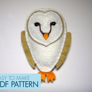 May include: A white felt owl with brown felt wings and orange felt feet. The owl has black eyes and a brown beak. The text "EASY TO MAKE PDF PATTERN" is on a blue background.