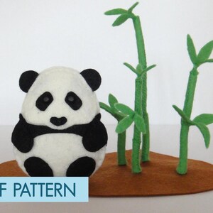 May include: A felt panda bear sitting on a brown felt base with green felt bamboo plants around it. The panda is black and white and has a cute expression. The text "PDF PATTERN" is at the bottom of the image.