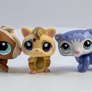 Puede incluir: Conjunto de seis pequeñas figuras de animales de plástico. Las figuras son marrones, beige, moradas y naranjas. Tienen ojos grandes y están en una variedad de poses.