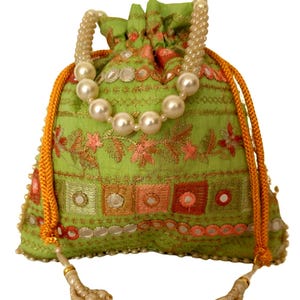 May include: A lime green drawstring pouch featuring intricate floral embroidery, small circular mirrors, and gold thread accents. The bag includes a pearl bead handle and two orange braided drawstrings with pearl-tipped tassels at the ends.