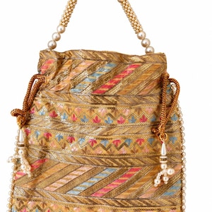 Puede incluir: Un bolso tipo saco con cordón en tono dorado que presenta un intrincado bordado en hilo rosa, azul y dorado. El bolso está adornado con hileras de pequeñas perlas blancas artificiales en los bordes y un asa de una sola hilera de perlas.