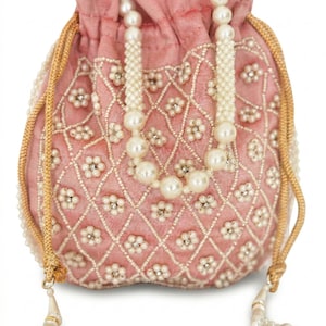 May include: A dusty pink drawstring pouch featuring a diamond-patterned grid of white beads and small floral accents made of pearls and clear crystals. The bag includes a pearl-beaded handle and gold-toned braided drawstrings with beaded tassels.