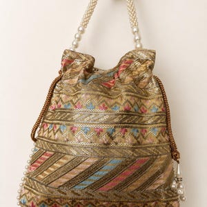 May include: A gold-colored drawstring bag with intricate embroidery and sequin details. The bag features a pearl beaded handle and a pearl trim along the bottom edge. The design includes pink, blue, and red accents.