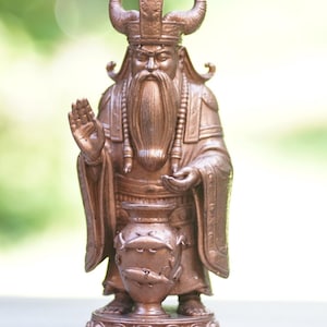 Peut inclure: Une figurine couleur cuivre représentant un personnage barbu portant un casque à cornes et des robes traditionnelles. Le personnage a une main levée dans un geste et se tient sur une base circulaire avec des sculptures décoratives.
