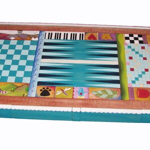 K&ouml;nnte beinhalten: Ein Holzspielbrett mit einer t&uuml;rkisblauen Oberfl&auml;che. Das Brett bietet mehrere Spiele, darunter Dame, Backgammon und ein Tic-Tac-Toe-artiges Spiel. Das Brett ist mit bunten bemalten Designs und dem Text "Say with hugs and kisses, be thankful, try new things" verziert.