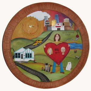 May include: A hand-painted wooden round platter with a cityscape, a couple holding a heart, a clock, a house, a road, and two cats. The platter has the text "Cherish Life Love Your Family Spend Time With Friends Never Ever Give Up Coronas On The Deck Run" around the edge.