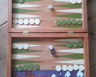May include: A wooden backgammon game board with a painted design. The top of the board features a grapevine and a farmhouse. The bottom of the board features a mountain scene with a snowman. The board is open and shows the game pieces in play. The dice show a 1 and a 6.