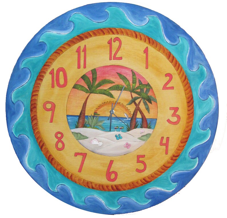 May include: A round wooden clock with a beach scene painted on the face. The clock has a blue and turquoise wave border and a rope-like design around the edge of the face. The numbers are in red and the hands are silver. The beach scene features palm trees, a sunset, and a sandy beach.